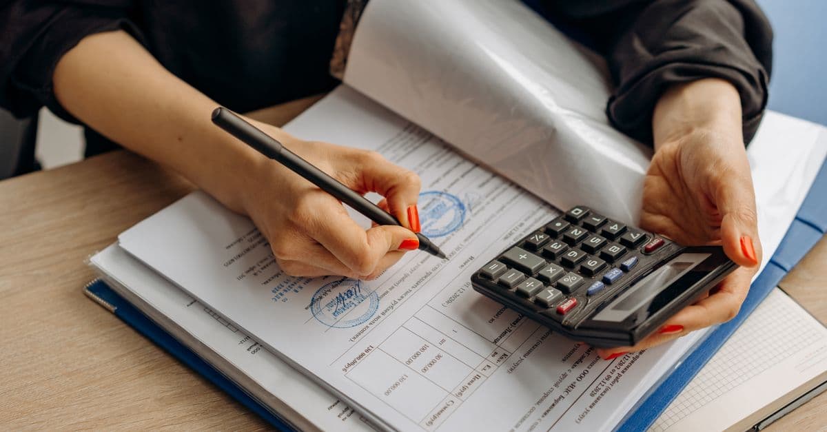 An accountant reviewing ledger numbers and journal entries on paper